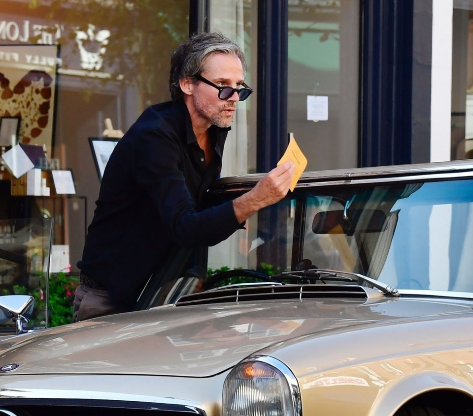 a man standing next to a car looking at a piece of paper