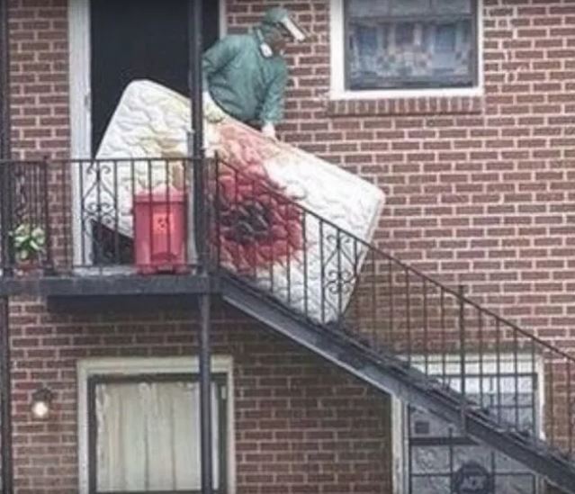 a man is carrying a mattress up the stairs of a brick building .