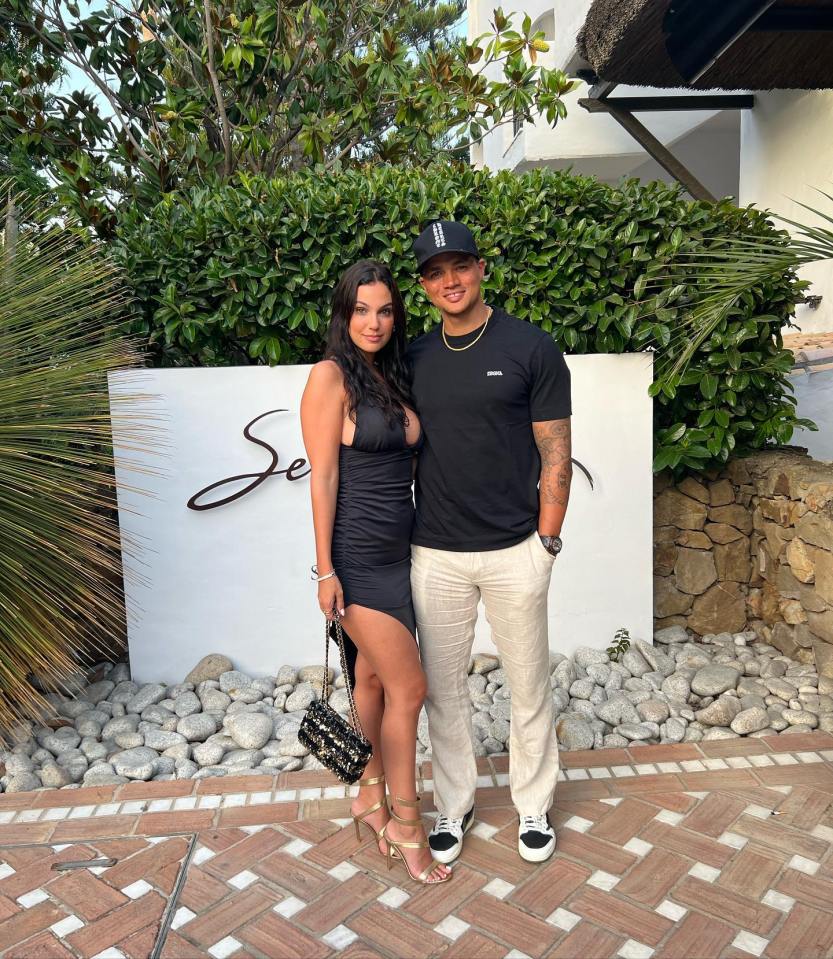 a man and woman pose in front of a sign that says sea