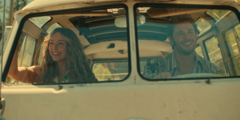 a man and a woman are sitting in a van and smiling