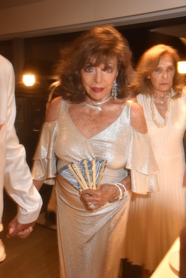 a woman in a silver dress is holding a fan