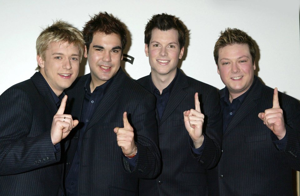 four men in suits are pointing up with their fingers