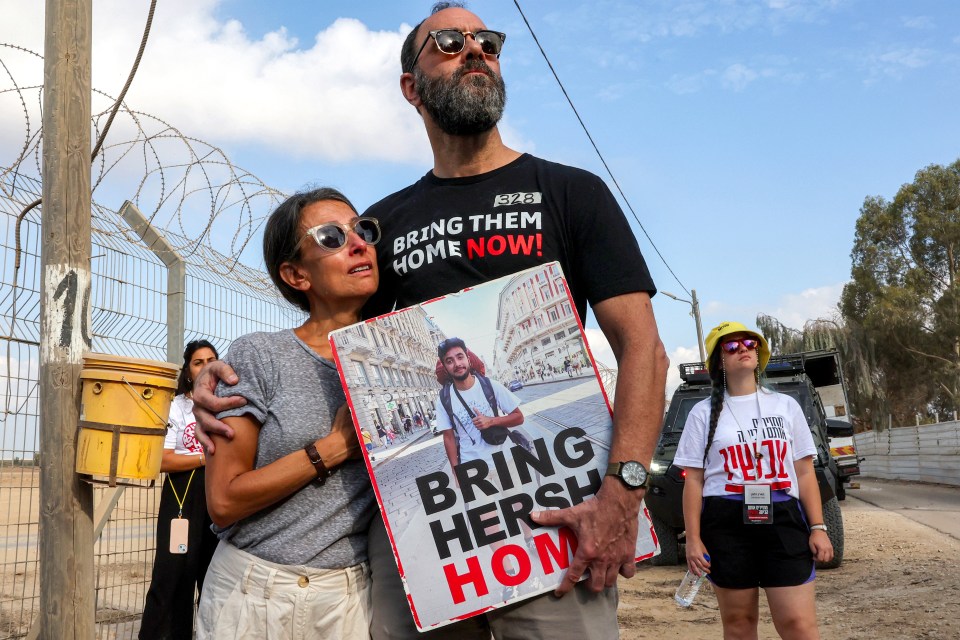 a man and woman holding a sign that says bring hersh home