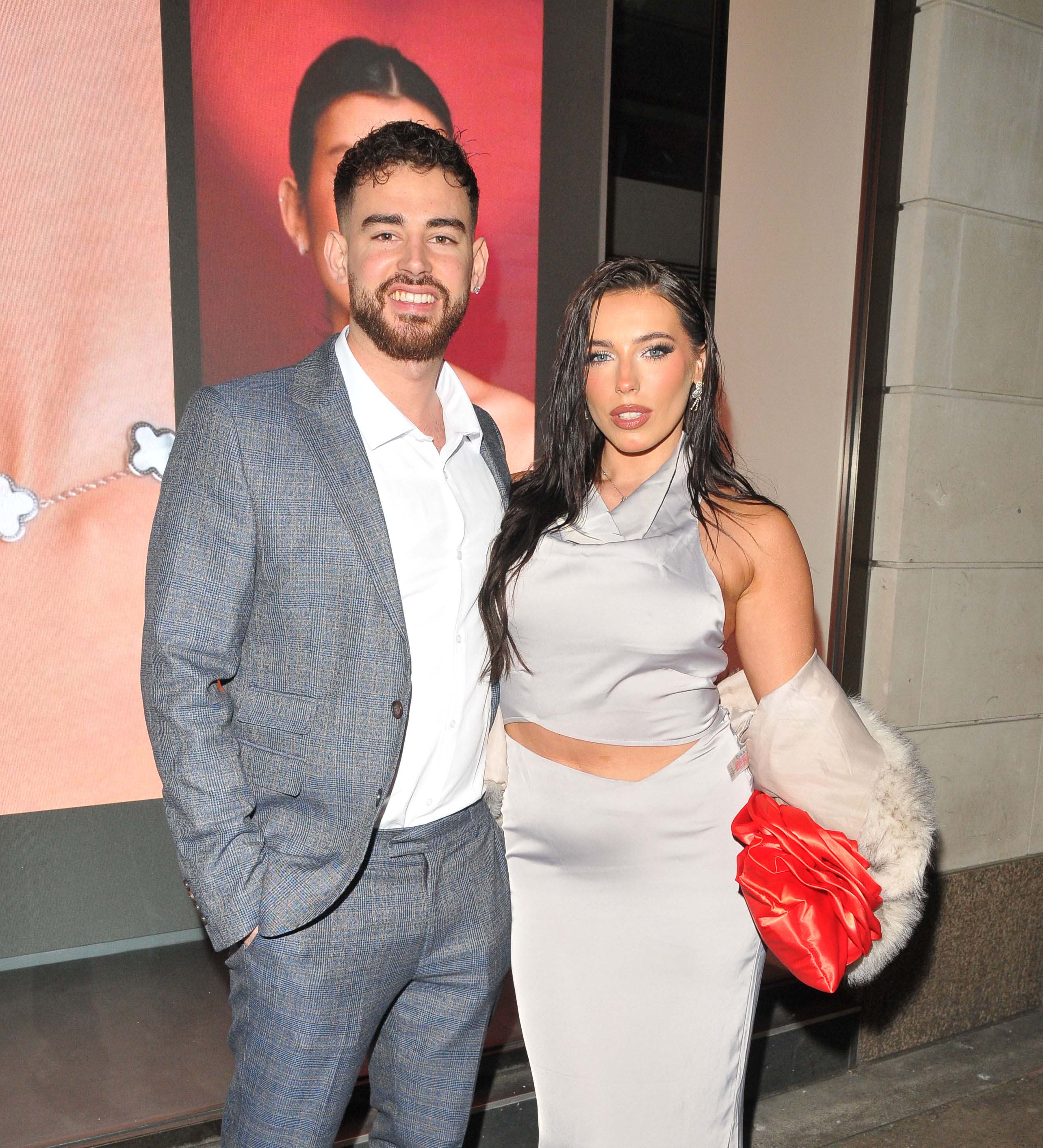 a man in a suit stands next to a woman in a white dress