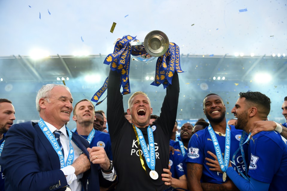 a man holding a trophy that says barclays on it