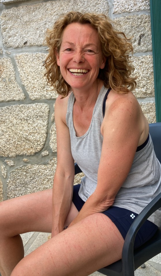 a woman wearing a grey tank top and black shorts smiles for the camera