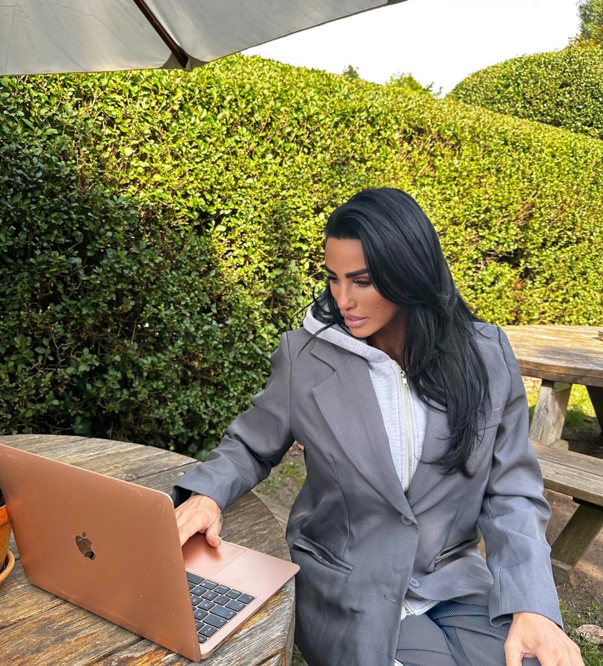 a woman sits at a table using an apple laptop