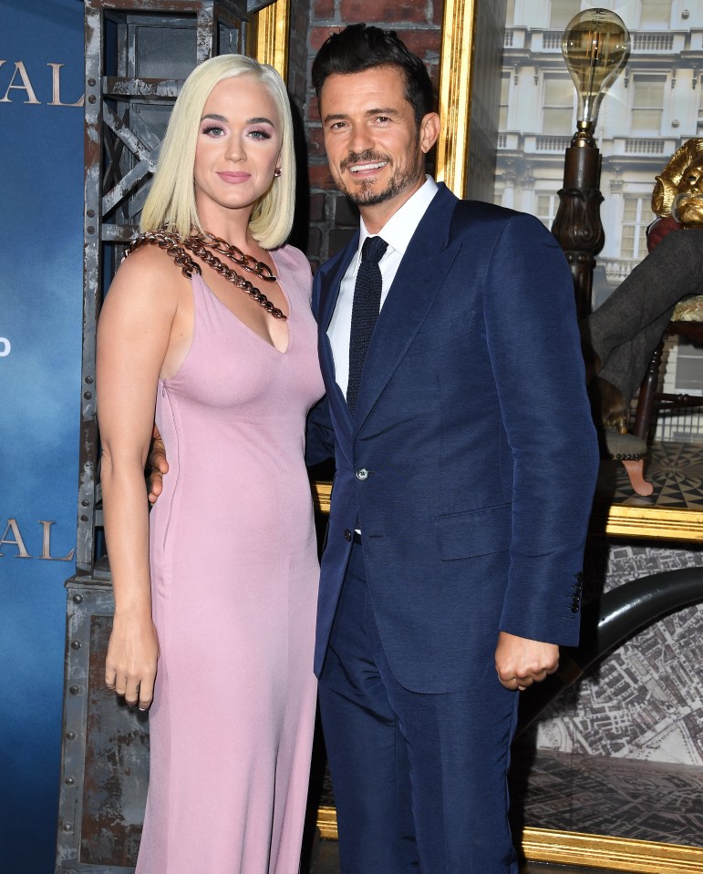 a man in a suit and a woman in a pink dress pose for a photo