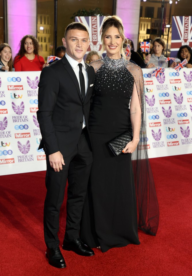 a man and a woman are standing on a red carpet sponsored by the mirror