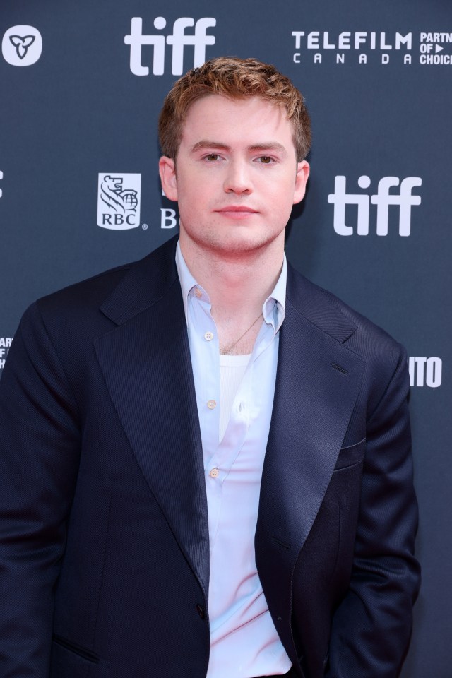 a man in a suit stands in front of a tiff sign