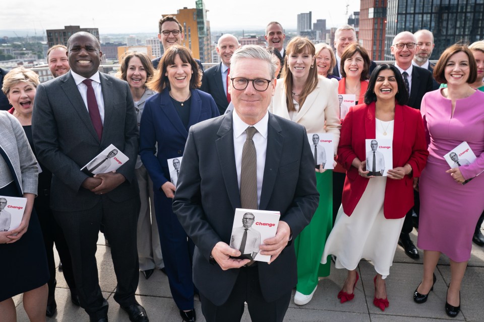 a group of people posing for a picture with a man holding a book that says change