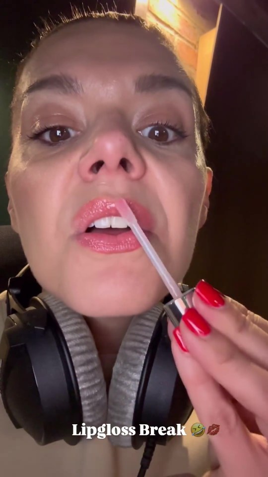 a woman wearing headphones is applying lipgloss to her lips