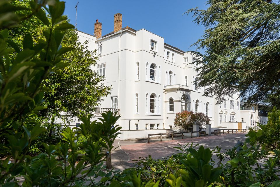 a large white building is surrounded by trees and bushes