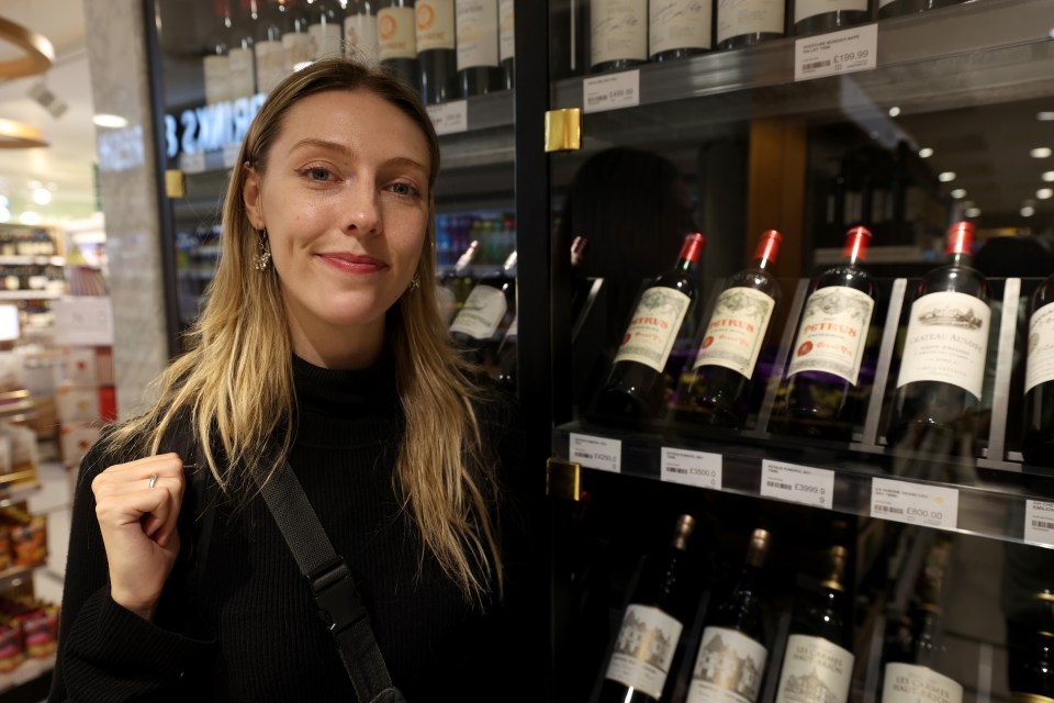 a woman stands in front of a bottle of bordeaux wine