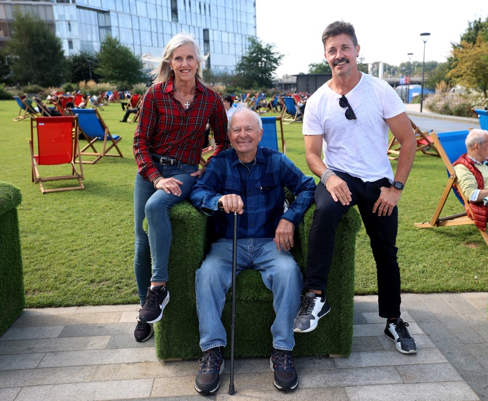 a man with a cane sits in a chair with two other people