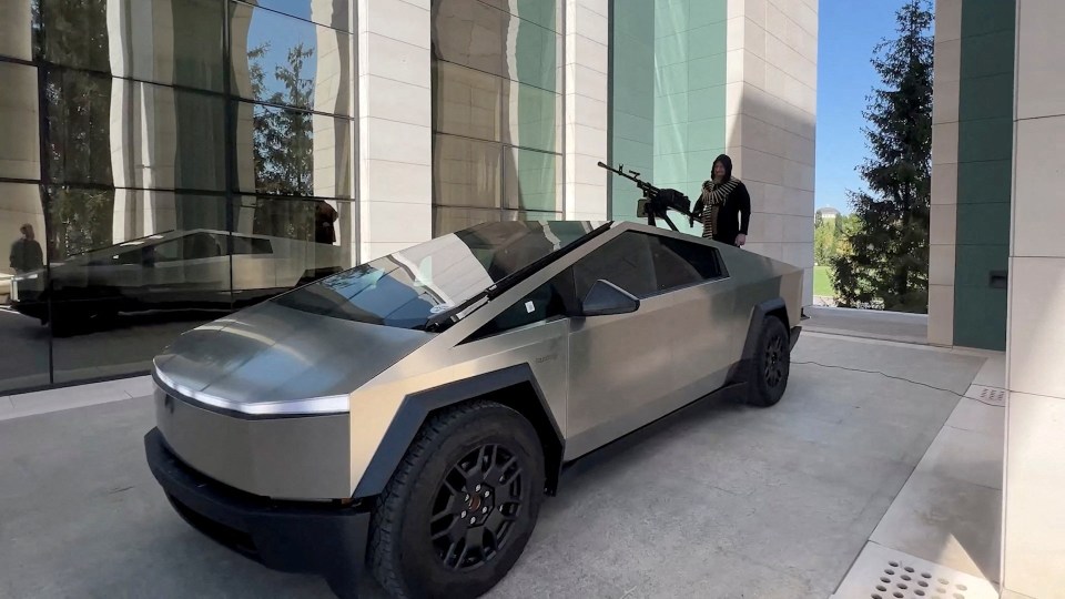 a silver tesla truck is parked in front of a building