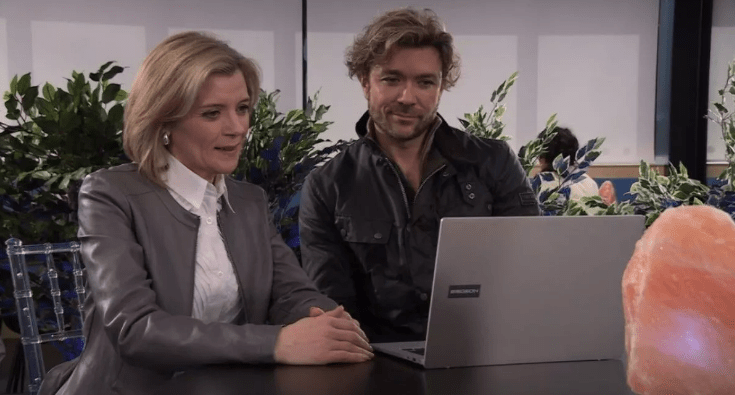 a man and a woman sit at a table looking at a laptop that says emachines