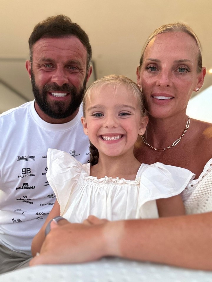 a man and woman pose with a little girl wearing a balenciaga shirt