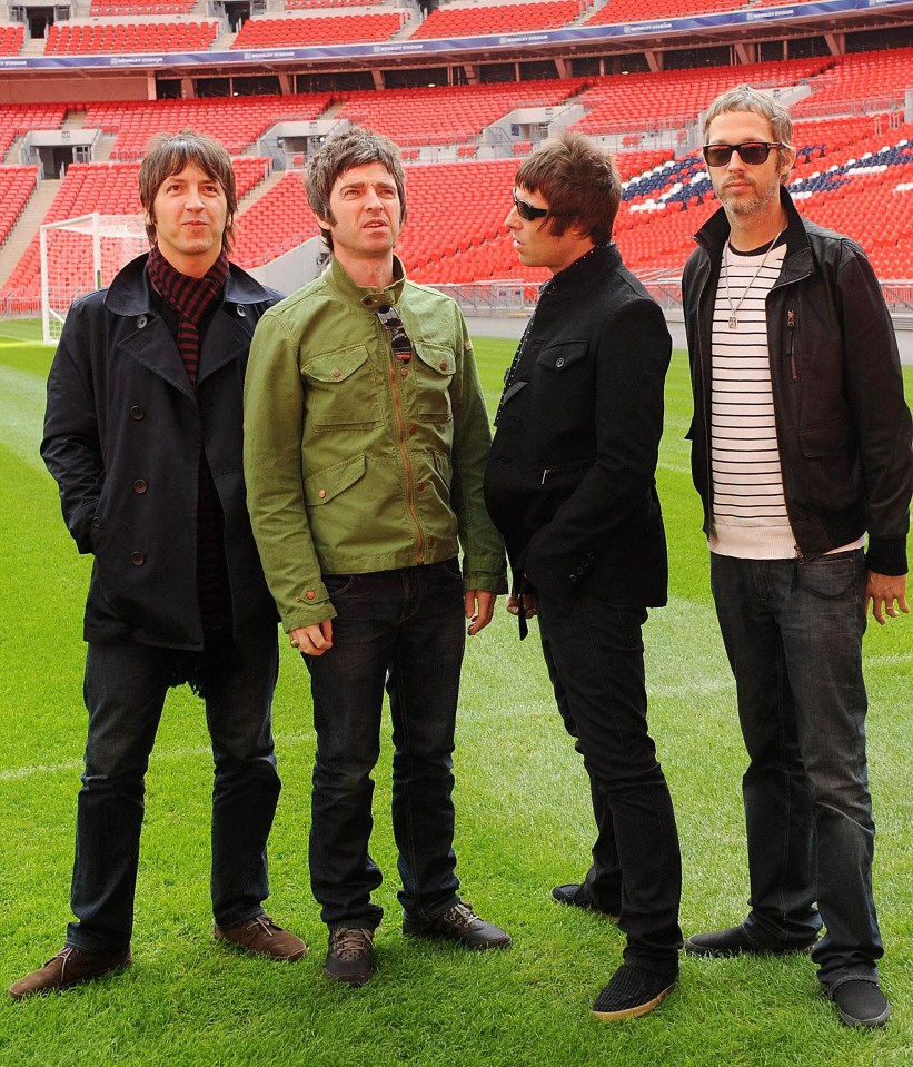 a group of men standing on a field with a stadium in the background