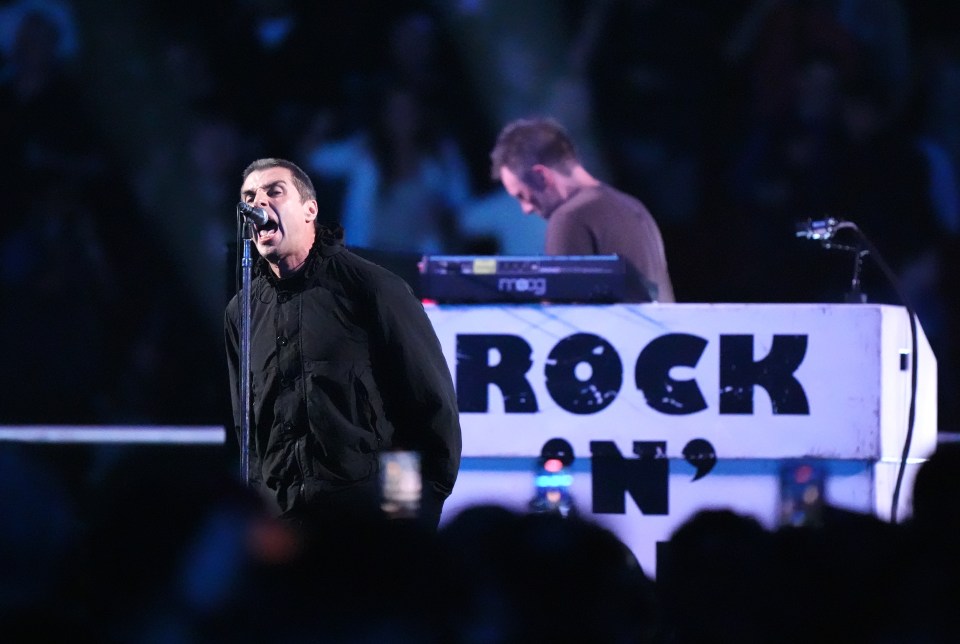 a man singing in front of a sign that says rock on