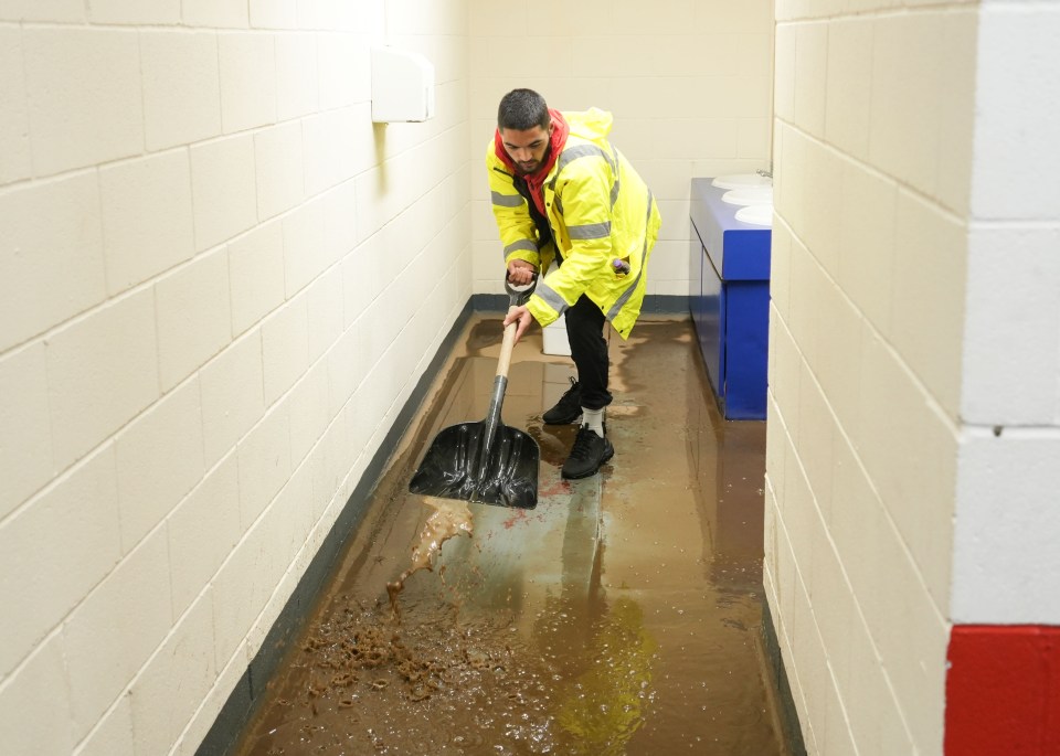 Staff clean the mud at AFC Telford Football Stadium after heavy rain