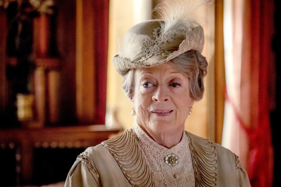 an elderly woman wearing a feathered hat and a brooch