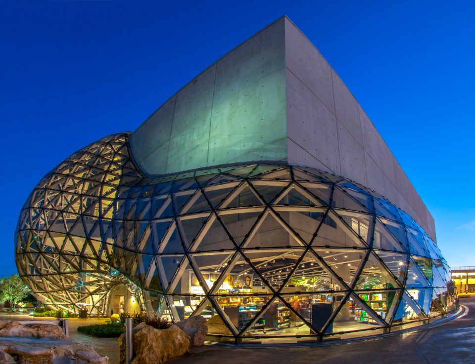 a building with a dome shaped glass facade is lit up at night