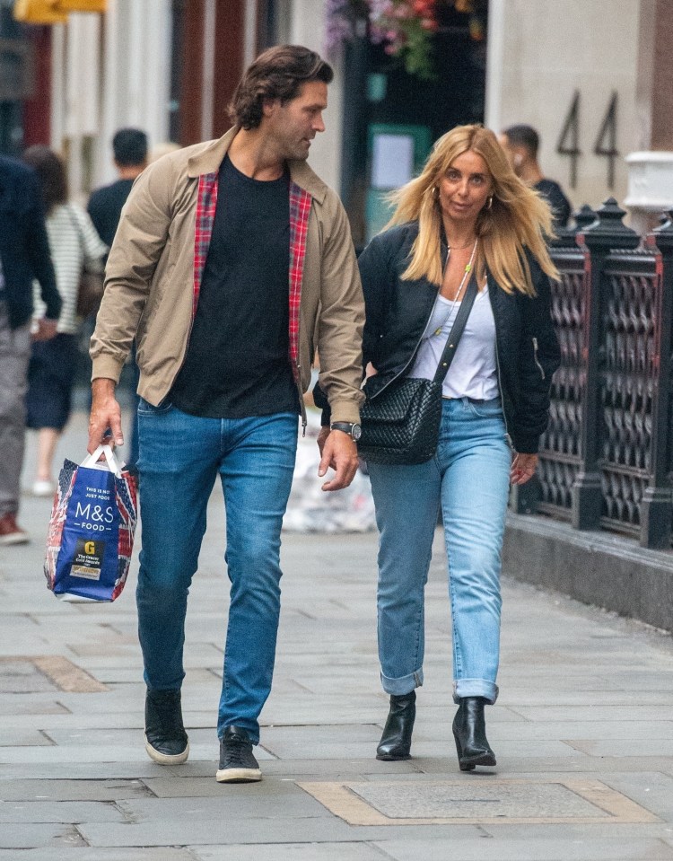 a man and woman walking down a street with a m & s bag