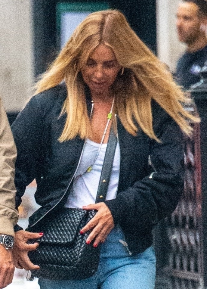 a woman in a black jacket is holding a black bag