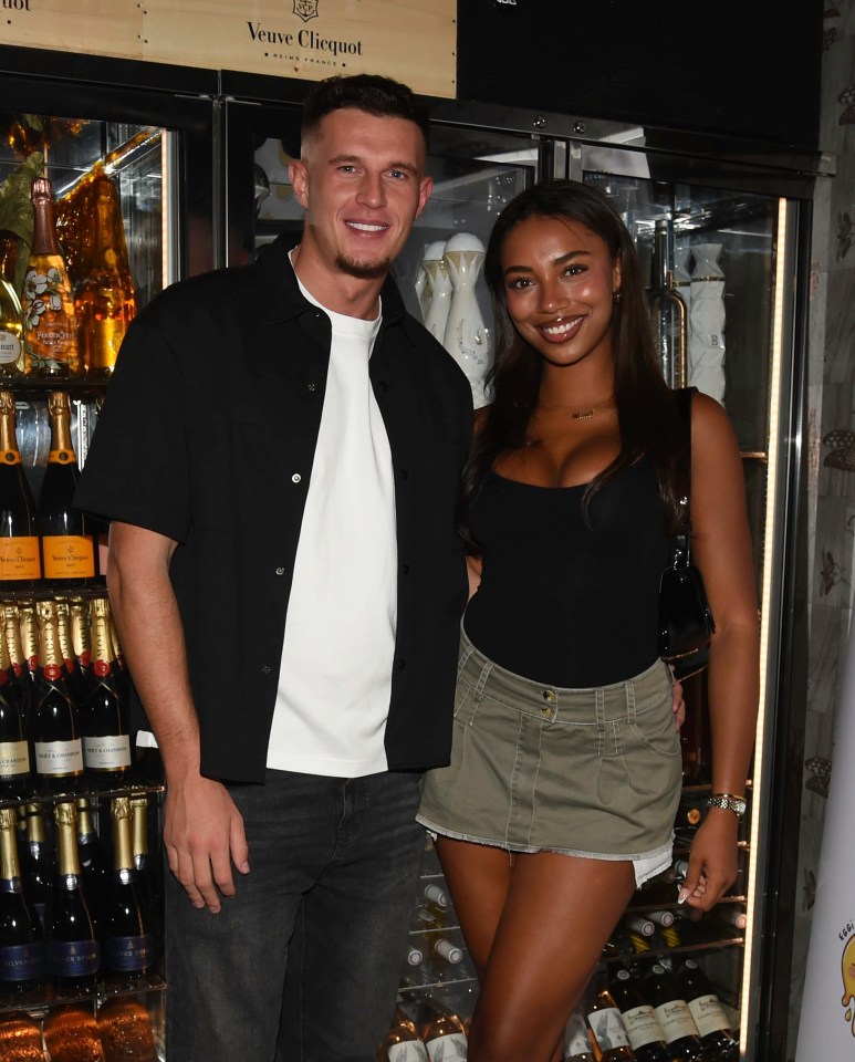 a man and woman pose in front of a veuve clicquot fridge