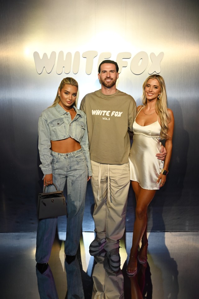 three people pose for a photo in front of a wall that says white fox