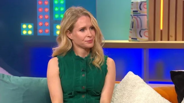 a woman in a green dress is sitting on a couch with a pillow .