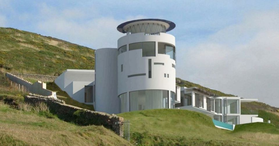 a large white house sits on top of a hill overlooking the ocean