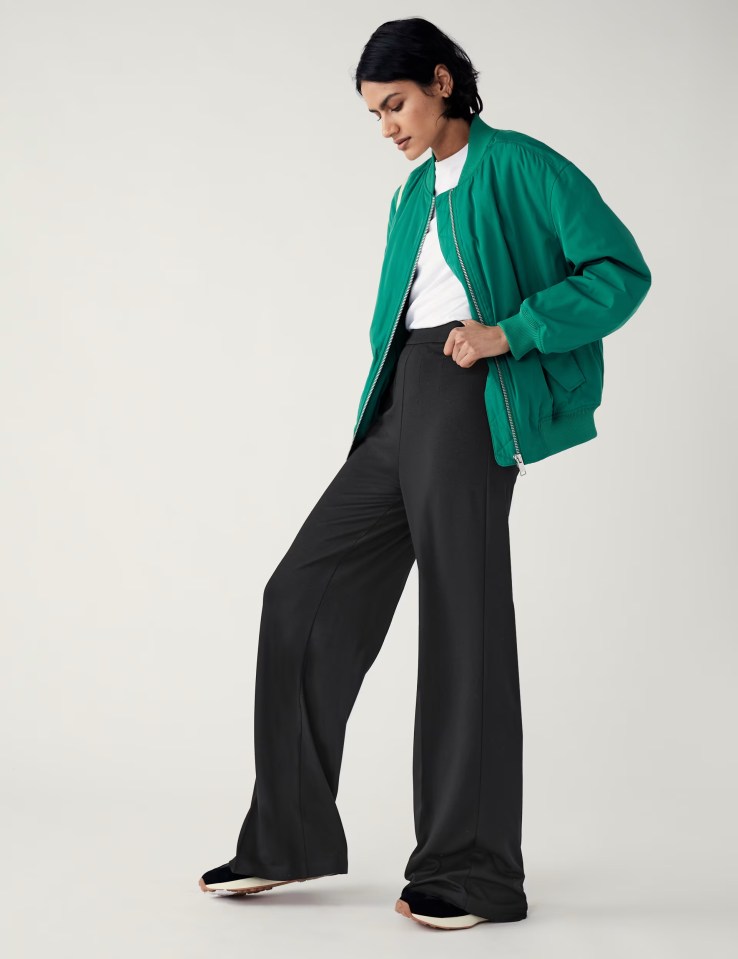 a woman wearing a green jacket and black pants