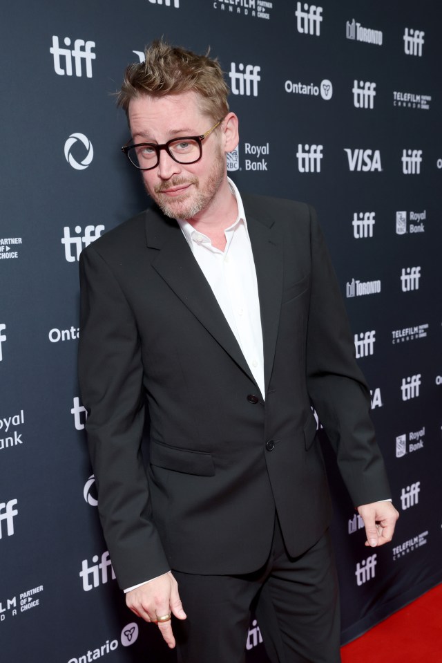 a man in a suit stands in front of a tiff sign