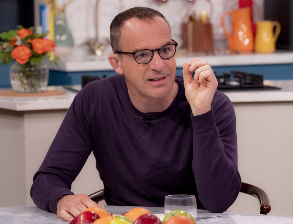 a man wearing glasses sits at a table with fruit