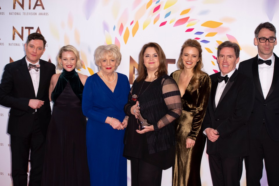 a group of people standing in front of a wall that says national television awards