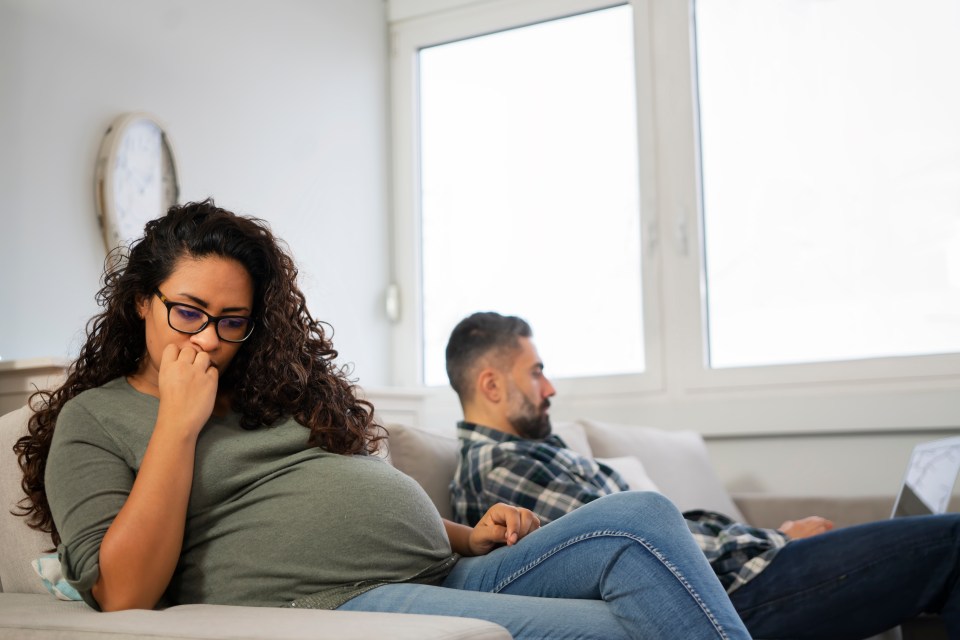 a pregnant woman sits on a couch next to a man