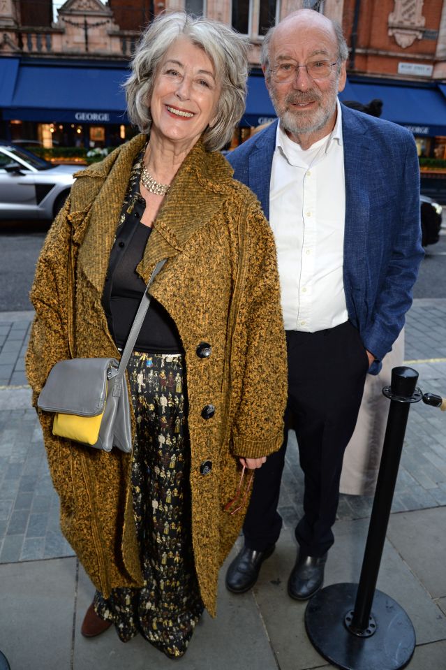 a man and a woman are posing for a picture in front of a store called george