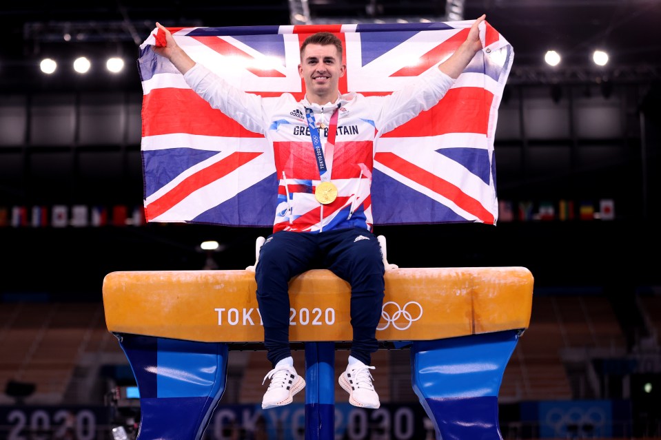 a man sitting on a balance beam holding a british flag