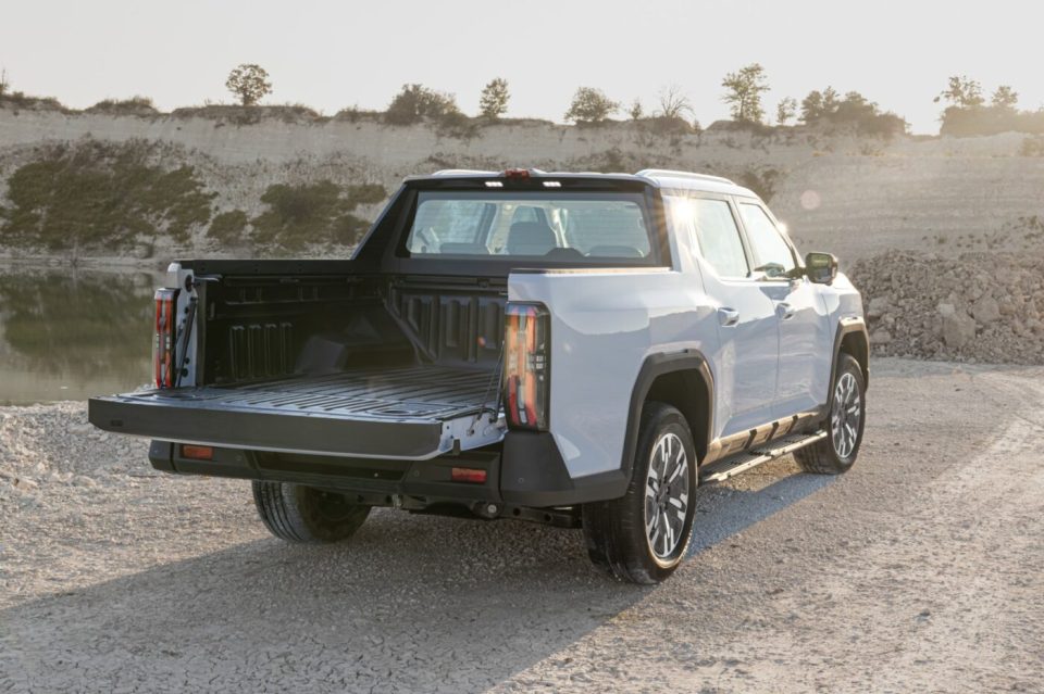 a white truck is parked on a dirt road near a body of water