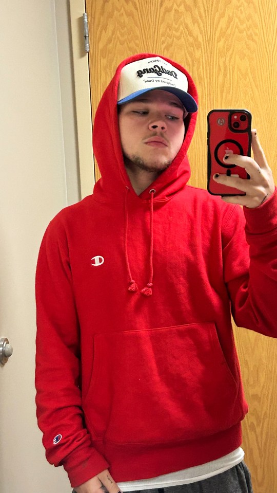 a man wearing a red champion hoodie takes a selfie