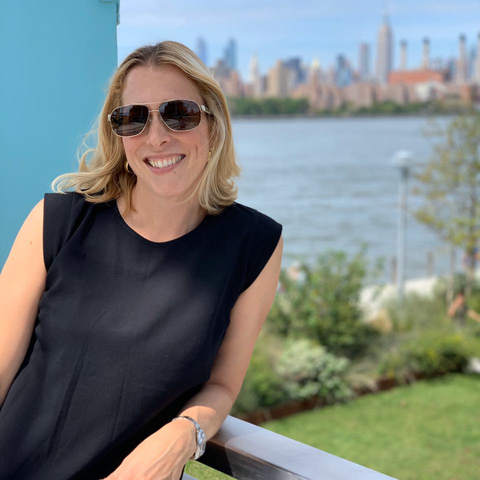 a woman wearing sunglasses stands in front of a city skyline