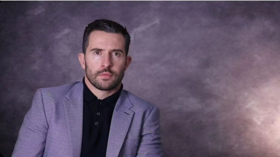 a man with a beard is wearing a purple jacket and black shirt