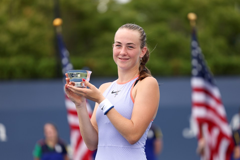 a woman in a nike shirt holds up a trophy