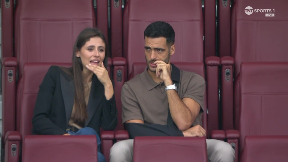 a man and a woman sit in a stadium watching tnt sports 1 live