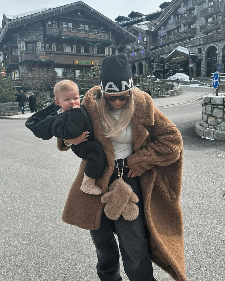 a woman holding a baby in front of a building that says rolex