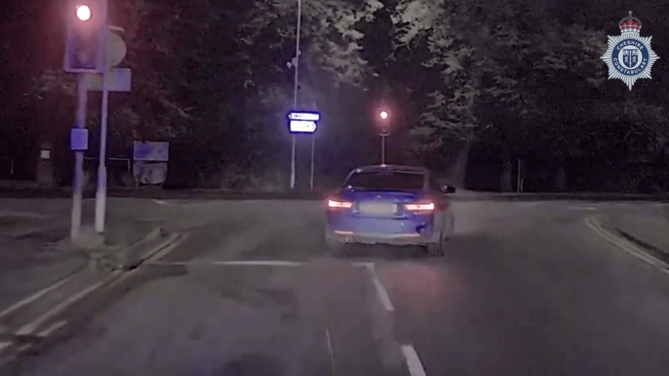 a blue car is driving down a street at night