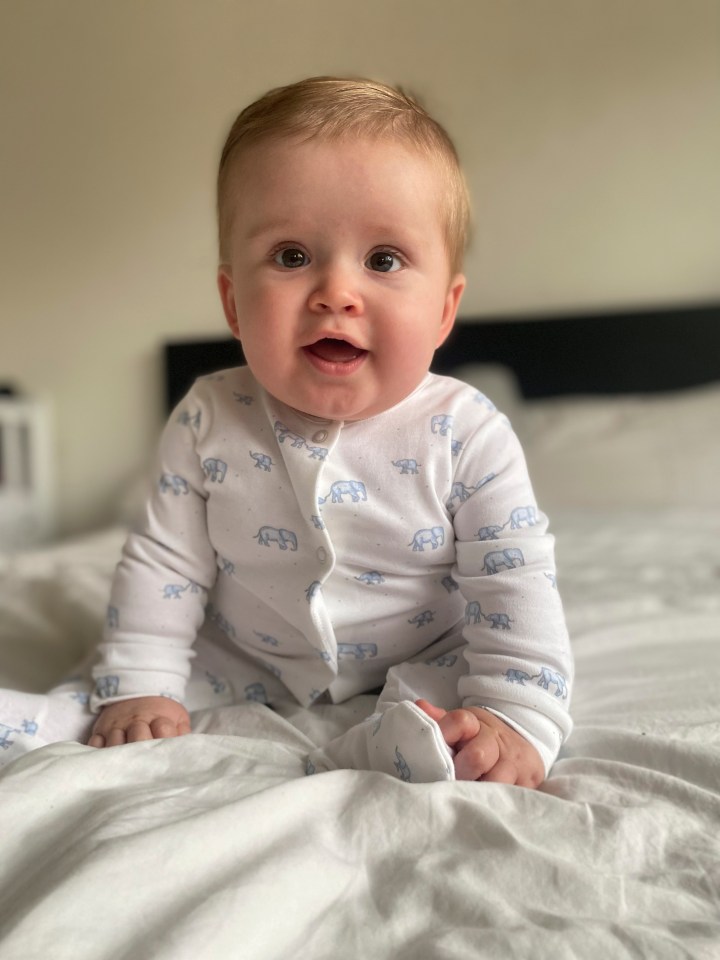 a baby wearing a white outfit with blue elephants on it