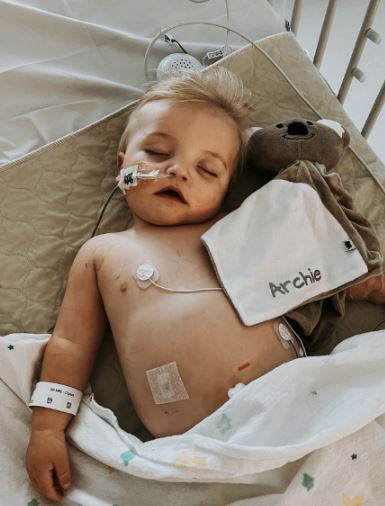 a baby is sleeping in a hospital bed with a stuffed animal .